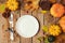 Autumn background with plate, fall leaves and pumpkin over wooden table.