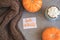 Autumn background with warm knitted scarf, blue mug with coffee, hot chocolate, cocoa, marshmallow, pumpkin, sign Hello