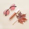 Autumn beauty or fashion composition â€“ bronze lip gloss  and pink sunglasses. Fall makeup concept