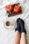 Autumn bed still life. Female legs in knitted socks and cup of coffee. Wooden tray with pumpkins, eucalyptus leaves