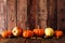 Autumn border arrangement of leaves, pumpkins and apples, side view against an old wood background