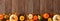 Autumn bottom border banner of pumpkins, gourds and fall decor on a rustic wood background