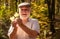 Autumn brings much joy. Happy pensioner collect autumn leaves in wood. Aged person happy smiling on autumnal landscape