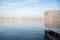 Autumn calm morning on meadow with a boat on the river. Beautiful sunrise over field with sunlight and mist