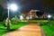 Autumn city park at night, trees with yellow leaves, street lights and benches