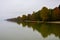 Autumn Colorful trees on the shore line of Ammersee lake in Bavaria in foggy gray weather