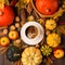 Autumn composition with cup of coffee, pumpkins, apples, nuts and cinnamons on dark rustic wooden background