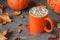 Autumn composition with a cup of hot aromatic cappuccino on dark stone table a surrounded by maple leaves and pumpkins. Fall time