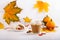 Autumn composition with cup of hot drink, delicious apple strudel   and colorful fall leaves on white background. Copy space.