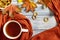 Autumn composition, a cup of hot tea, a warm terracotta scarf, fallen leaves and drying on the background of a blue wooden table.
