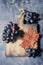 Autumn composition with cutting wooden board, marple leaves, freshly harvested ripe grapes, cones and wallnuts on dark stone table