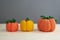 Autumn composition of three pumpkins, knitted decor of orange and yellow pumpkins on a gray background, yarn and needlework, soft