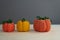 Autumn composition of three pumpkins, knitted decor of orange and yellow pumpkins on a gray background, yarn and needlework, soft