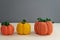 Autumn composition of three pumpkins, knitted decor of orange and yellow pumpkins on a gray background, yarn and needlework, soft