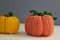 Autumn composition of two pumpkins, knitted pumpkin decor of orange and yellow on a gray background, yarn and needlework, soft