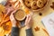 Autumn concept. First person top view photo of female hands in jumper holding cup of coffee wicker tray with cookies plaid notepad
