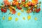 Autumn concept with pumpkins, flowers, autumn leaves and rowan berries on a turquoise background. Festive autumn decor, flat lay