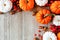 Autumn corner border of orange & white pumpkins, berries on gray wood