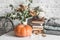 Autumn cozy home still life. Pumpkin, dry branch pitcher, stack of books, pile of winter autumn sweaters,  teddy bear on the