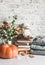 Autumn cozy home still life. Pumpkin, dry branch pitcher, stack of books, pile of winter autumn sweaters,  teddy bear on the
