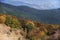 Autumn deciduous and coniferous forests, and a city in the valley in the background.