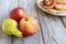 Autumn delicious apples and pear and a plate of pastry on wooden background