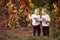 Autumn emotional portrait of little twin girls. Pretty little girls with red grape leaves in autumn park. Autumn activities for