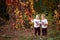 Autumn emotional portrait of little twin girls. Pretty little girls with red grape leaves in autumn park. Autumn activities for