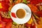 Autumn, fall leaves, hot steaming cup of coffee and a warm on table background. Seasonal, morning coffee, Sunday relaxing and