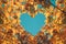 Autumn fall love background. Orange and yellow leaves in heart shape of background of blue sky. Heart-shaped sky through autumn