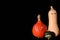 In autumn, a family of brightly colored, different ornamental gourds stands side by side against a dark background with shiny eyes