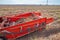 Autumn field with onion crop grown by drip irrigation technology. A tractor-mounted trailed root harvester working. The bulbs are