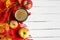 Autumn flatlay background with cup of coffee, yellow leaves and and red apples on white wooden table, copy space