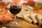 Autumn flavors and colors: a glass of red wine with slices of wholemeal bread in the background on an old wooden cutting board