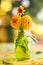 Autumn floral bouquet made of fresh yellow dahlia in green vase on blurred green background with festive bokeh