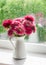 Autumn flowers asters in a white pitcher against the window on a rainy day