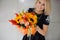 Autumn flowers in hands of woman. Pumpkin, sunflowers and other flowers