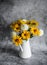 Autumn flowers yellow and white dahlias bouquet in a vintage white metal jug on a gray background, front view