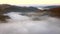 Autumn fog floats over the countryside at sunrise.