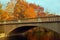 Autumn foliage surrounds a stone bridge spanning a lake