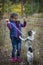 In the autumn forest, a little girl is training a French bulldog