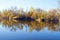 Autumn forest reflected in the calm waters of a lake makes a mirror effect