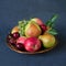 Autumn fruit mix - fresh apples, pears, grapes and plums in a wicker wooden plate. Dark blue background. Harvest concept