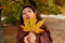 Autumn Funny Face. Asian Woman Holding Yellow Maple Leaves In Park.