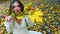 Autumn girl blowing on bouquet of fall leaves