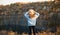 Autumn girl in blue sweater and hat standing backwards and admire nature lake view. Autumn forest colors with girl back view