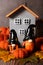 Autumn gnomes hand-painted against the background of a gray decorative house and knitted pumpkins