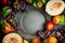 Autumn harvest fruits and vegetables around blank dark vintage dish, top view