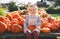 Autumn harvest of pumpkins. Child picking orange pumpkin at farm market or seasonal festival. Cute little girl playing among