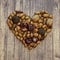 Autumn heart shape by various nuts and acorns on a wooden background